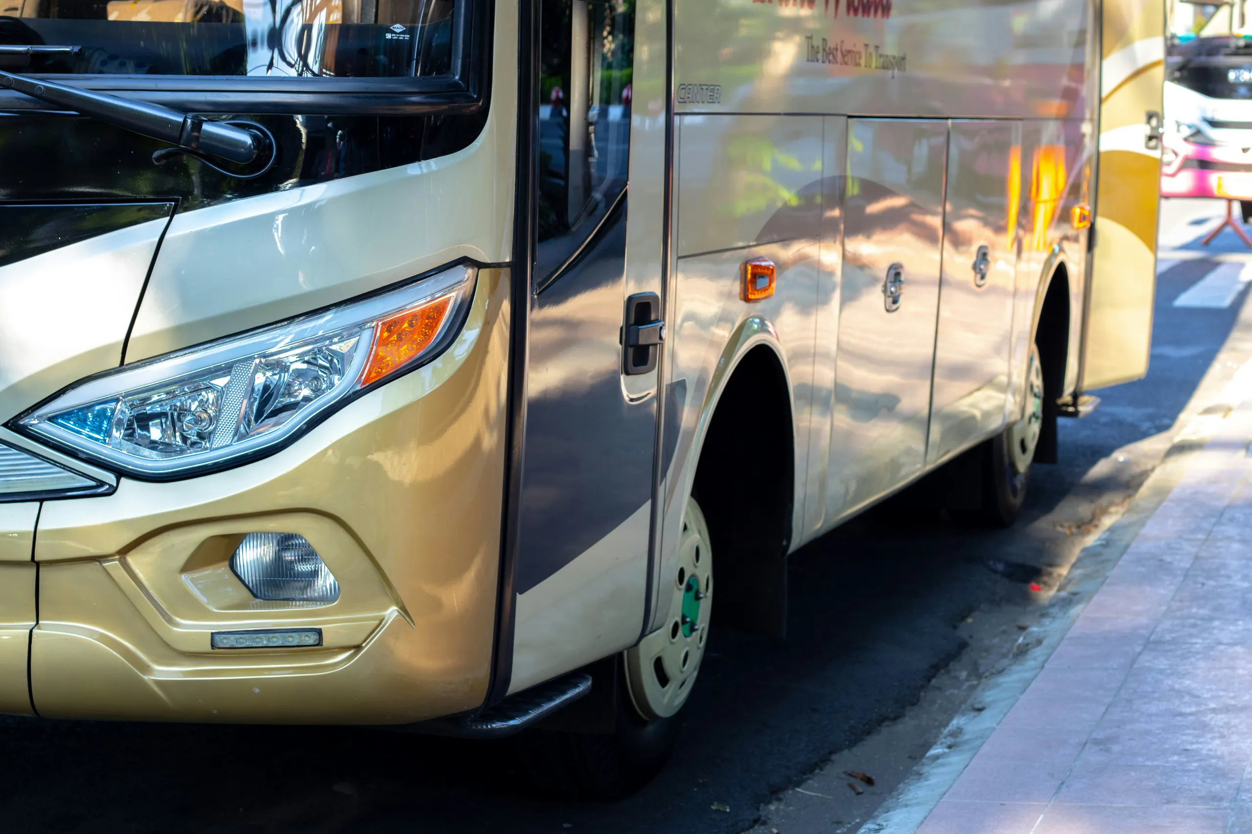 Duży złoty autobus turystyczny zaparkowany przy ulicy